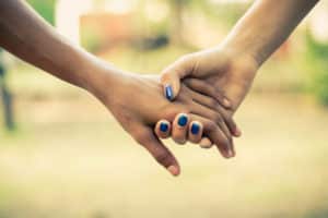 Two hands holding each other outdoors