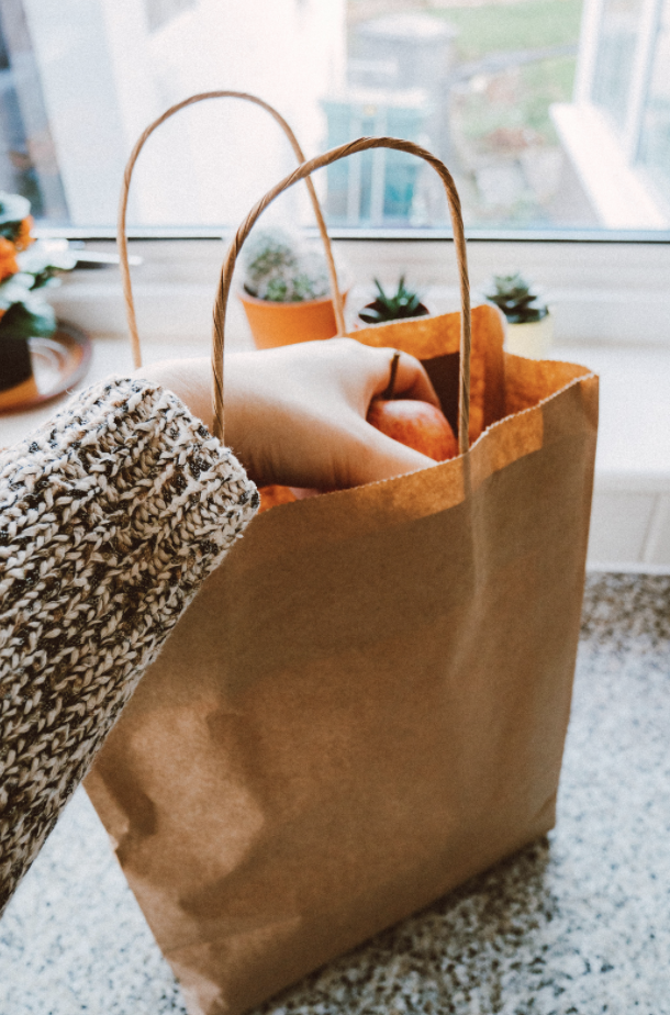 Woman's hand reaching into a brown paper bag filled with groceries