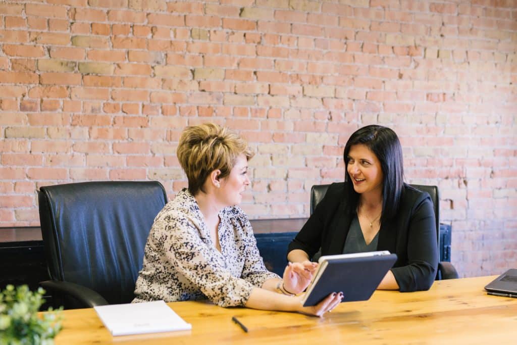 Two women conversing in front of a laptop