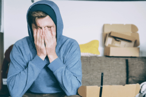 Young man sitting on couch with head in his hands