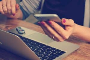 Woman looking at her phone with laptop open