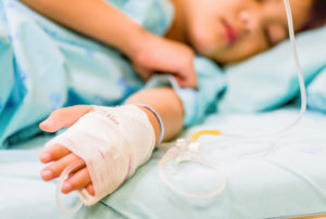 Child sleeping in hospital bed with IV in arm