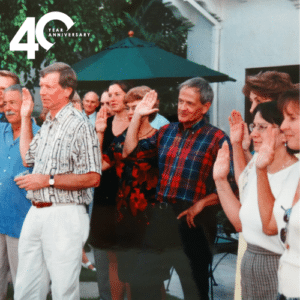 A graduating class of Court Appointed Special Advocate volunteers with their hands raised for the oath.