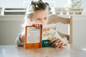 Young girl sitting at table engrossed in a picture book