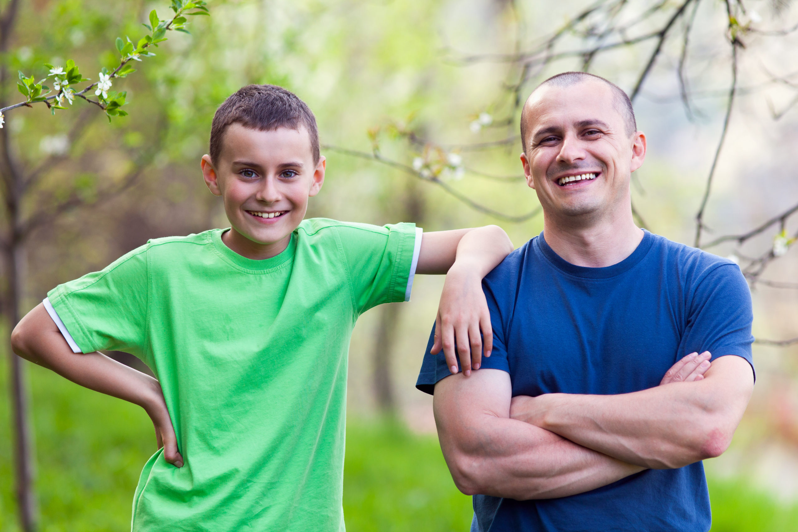 Man and young boy outdoors smiling at camera