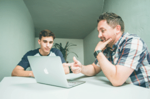 Man and teenage boy studying on a laptop