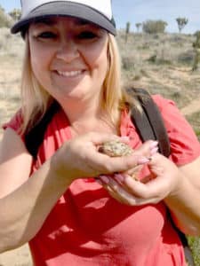 Smiling Voices for Children staff member Brianna holding a lizard at volunteer event