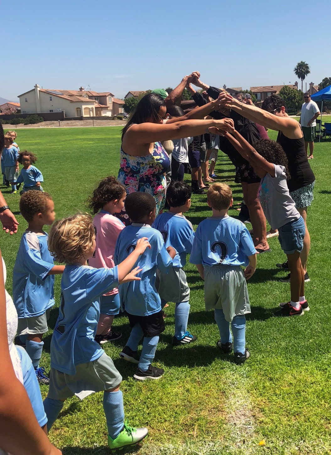 Children running under a tunnel of outstretched arms at volunteer event