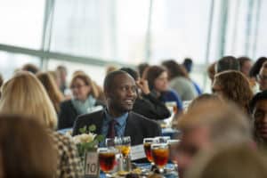 Smiling volunteer seated for dinner at Judges' Luncheon event