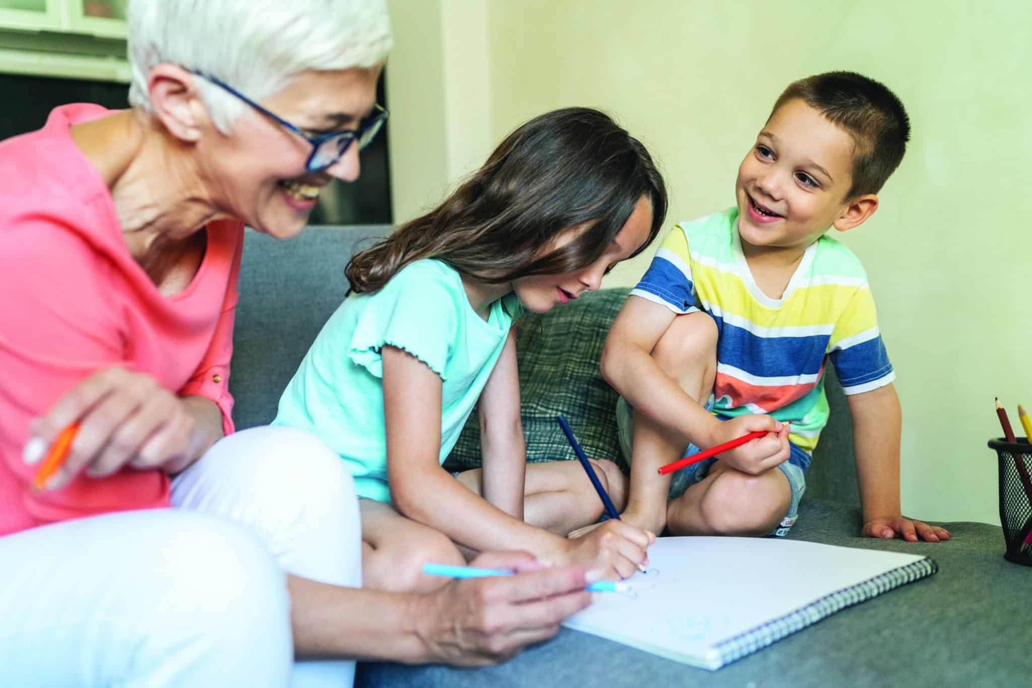 Drawing with grandma Happy grandmother coloring with her grandchildren at home