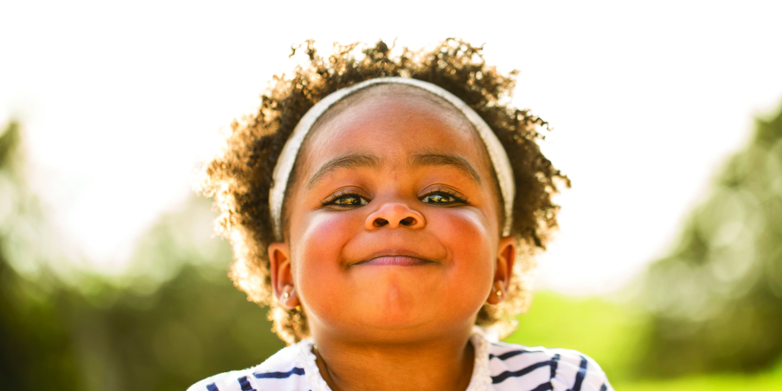 Happy African American little girl laughing and smiling outside.